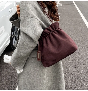 Detail of burgundy faux suede bucket bag with drawstring closure and shoulder strap