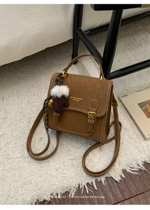 Detailansicht eines Vintage braunen Kunstleder Rucksacks mit Plüschanhänger auf Teppich