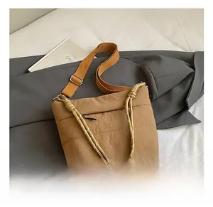 Detail view of khaki nylon bucket bag with orange webbing strap and woven rope handle