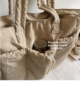 Detail of beige tote bag showing adjustable drawstring pocket holding a thermos bottle
