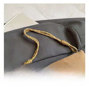 Detail showing the ginger yellow braided rope handle and knotted nylon fabric bag