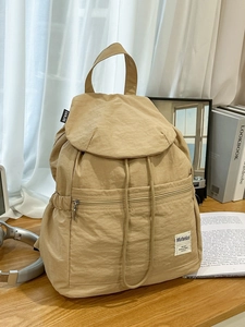 Sac à dos en nylon kaki avec cordon de serrage et rabat sur un bureau en bois