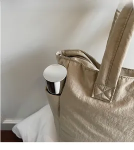 Close-up of a nylon tote bag side pocket holding a water bottle in a minimalist setting