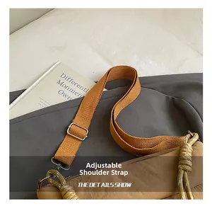 Detail showing adjustable nylon shoulder strap with silver buckle on brown crossbody bag