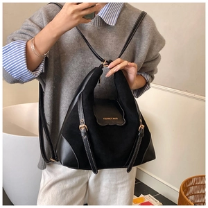 Détail du sac bandoulière en daim noir avec surpiqûres blanches et boucles dorées