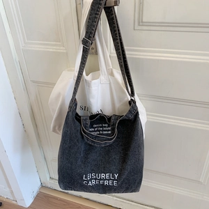 Detail of black denim bucket bag with white Leisurely Carefree printed slogan text