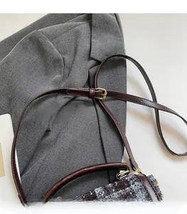 Detail of adjustable brown leather shoulder strap with gold buckle on tweed bag