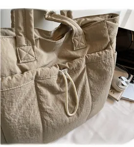 Detail of khaki nylon puffer tote bag with drawstring opening and reinforced stitching