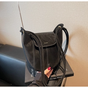 Détail du sac seau en cuir noir avec surpiqûres blanches et logo Fashion discret