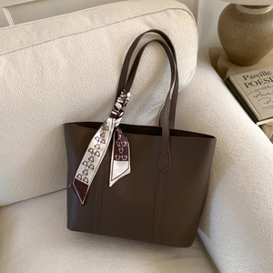 Detail of dark brown tote bag on sofa with decorative heart and bear print silk scarf