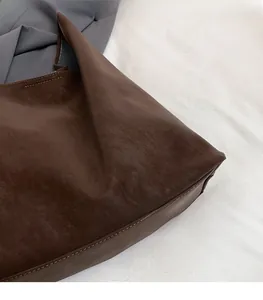 Close-up of dark brown leather tote bag showing fine texture and reinforced stitching