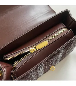Macro view of gold metal zipper and tweed fabric detail on a brown leather handbag