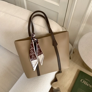 Close-up of khaki leather tote bag featuring dark brown contrast straps and bear print scarf