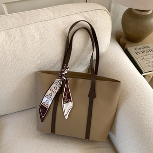 Detail of vintage tote bag with smooth faux leather and decorative bear scarf on sofa