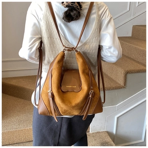 Gros plan détaillé des textures contrastées en daim marron et cuir sur le sac à bandoulière