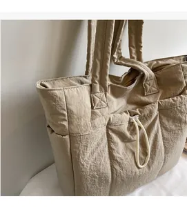 Close-up of khaki padded tote bag showing pleated nylon texture and reinforced shoulder strap