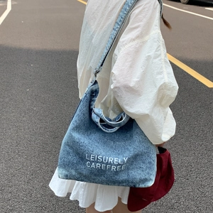 Detail of blue washed denim bucket bag featuring white Leisurely Carefree lettering