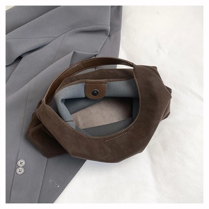 Detail of dark brown leather tote with magnetic buckle closure and soft suede lining