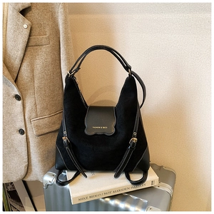 Détail du sac à main noir mat avec boucles dorées posé sur une valise argentée
