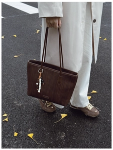 Close-up of woven texture tote bag in dark brown with elegant beaded tassel accessory