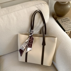 Detail of minimalist cream tote bag with brown straps and cute bear pattern scarf