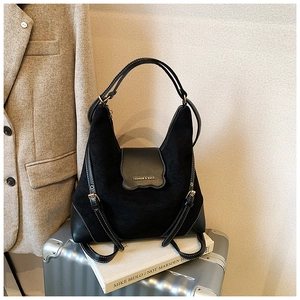 Détail du sac bandoulière vintage noir mat avec logo sur une valise argentée