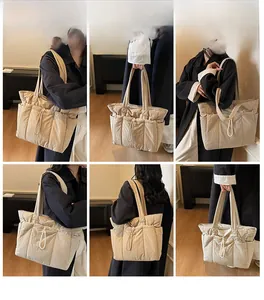 Detail view of beige quilted tote bag showing drawstring design and side pockets on strap
