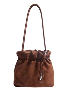Chic brown suede bucket bag with drawstring closure and metallic tag on white background