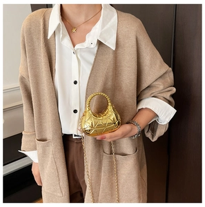 Gros plan du mini sac doré avec texture matelassée géométrique sur un pull en maille