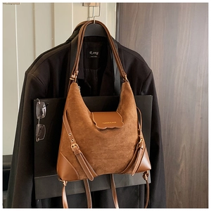 Détails des textures de daim et logo doré sur un sac à bandoulière marron rétro