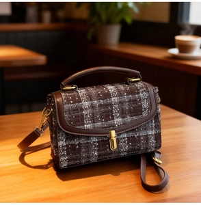 Detailed view of vintage plaid pattern and premium brown leather on a chic shoulder bag