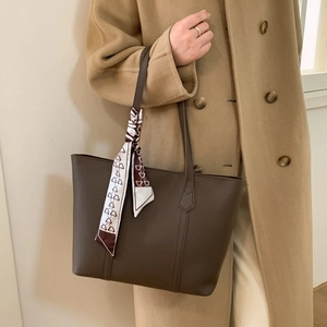Close-up of large brown leather tote bag featuring a decorative heart print silk scarf detail