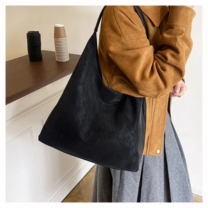 Minimalist black matte hobo bag shown on shoulder in a bright aesthetic interior