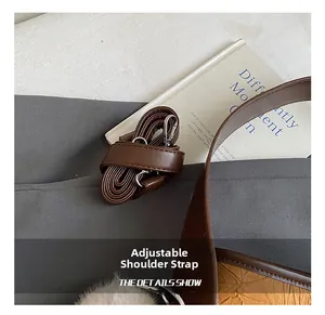 Detailed macro view of adjustable brown faux leather shoulder strap and silver metal buckle