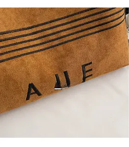 Close-up of brown suede material featuring black embroidery and fine stitching details