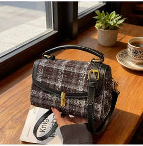 Close-up of retro plaid tweed handbag with black leather trim and gold metal twist lock