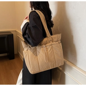Detail view of khaki quilted puffer tote bag with front drawstring pocket and soft texture