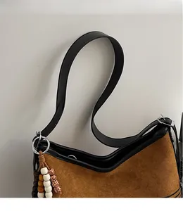 Detail of retro faux suede tote bag featuring smooth black leather strap and beaded pendant