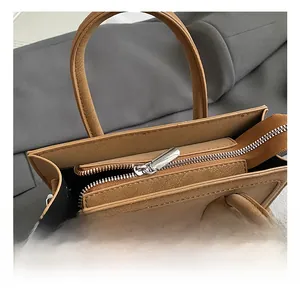 Close-up of the silver metal zipper closure and litchi texture on brown tote bag