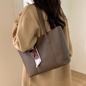 Detail of a large vintage brown leather tote bag with decorative silk scarf on shoulder