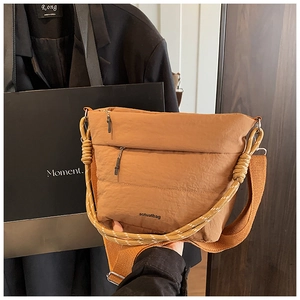 Detail of caramel brown crossbody bucket bag with dual rope straps and logo lettering