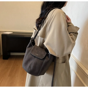 Détail du sac à bandoulière gris foncé mat avec surpiqûres blanches et logo doré
