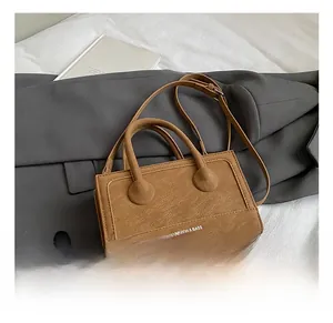 Detail of vintage brown textured leather handbag with top handles and adjustable shoulder strap