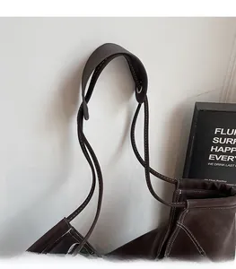 Détail de la large bandoulière en cuir avec surpiqûres blanches sur un sac cabas marron