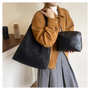 Detailed view of black minimalist shoulder tote bag set with matching pouch on a model
