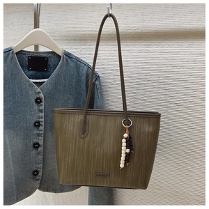 Detail of olive green textured tote bag with elegant beaded charm and brand logo