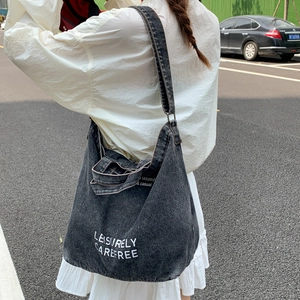 Detail of black denim tote bag showing artistic LEISURELY CAREFREE text print and texture