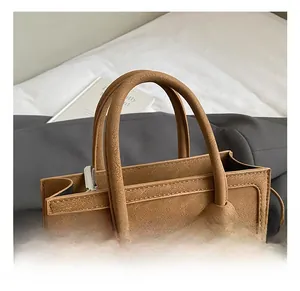 Close-up of retro brown textured leather handbag featuring thick handles and silver zipper