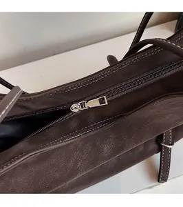 Détail de la fermeture éclair en métal argenté et du cuir marron texturé du sac
