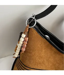 Detail of colorful beads and wooden charm attached to a brown suede tote bag